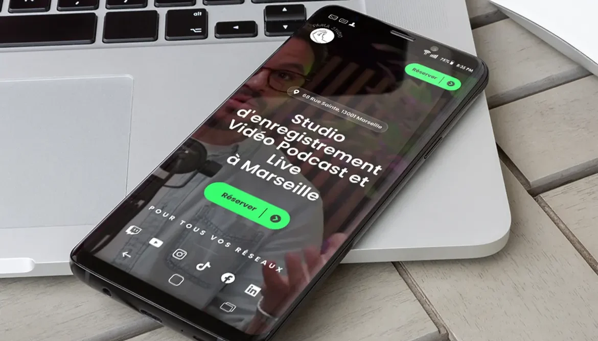 Mobile posé sur le bord du clavier d'un laptop affichant le site web mobile du Parla Studio à Marseille